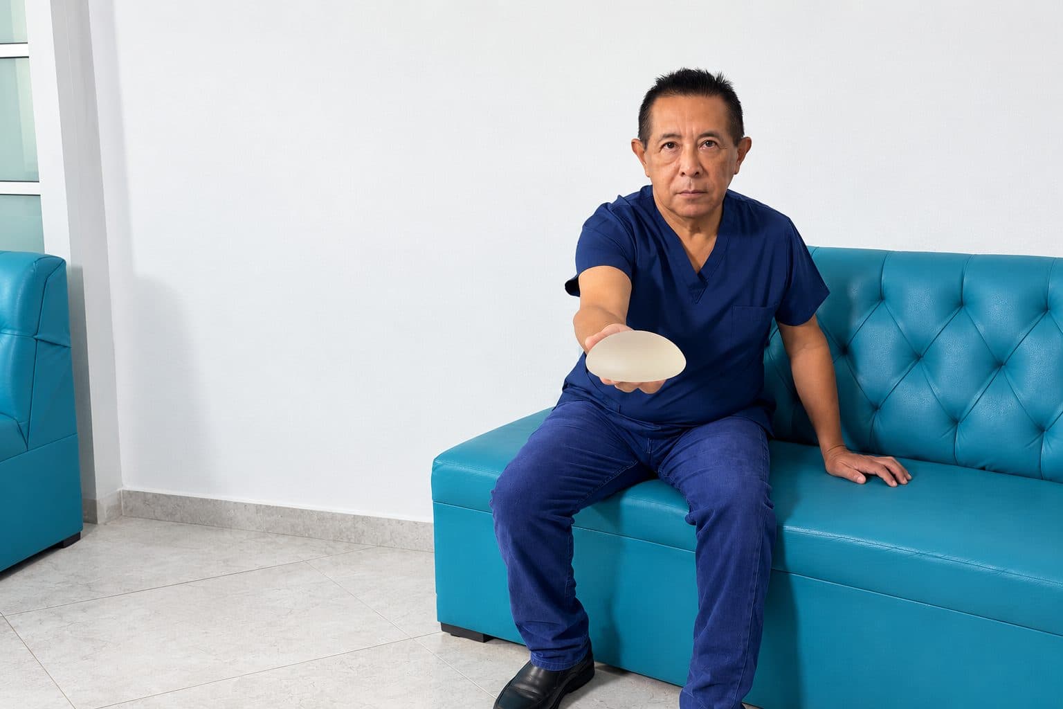 Dr. Carlos Alejos, cirujano plástico en Cancún, sosteniendo un implante mamario